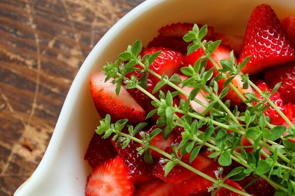 Rote Erdbeeren in einer Untertasse mit grünen Zweigen