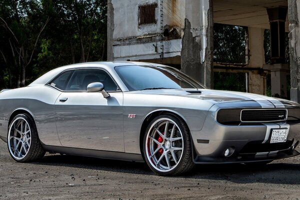 A gray dodge CAR on the background of an abandoned building