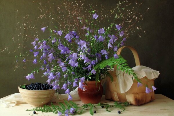 Bouquet of bluebells, blueberries, basket on the table