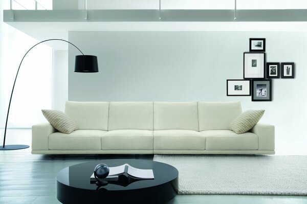 Living room with a white sofa and a black floor lamp with frames on the wall