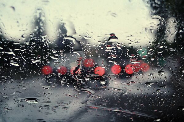 Raindrops on the glass against the background of headlights