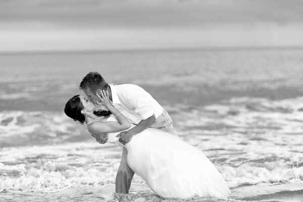 A man and a woman at a wedding kiss on the shore