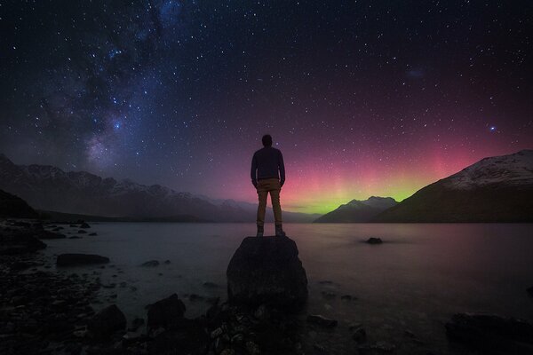 Hombre en el fondo de la Aurora boreal y el cielo estrellado