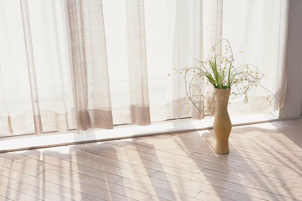 A bright room with curtains and a white vase