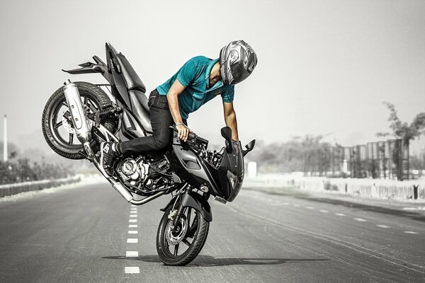 Ein Motorradfahrer macht einen gefährlichen Stunt auf einem schwarzen Motorrad mitten auf der Straße