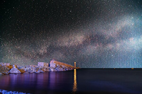 The bay of the lighthouse illuminates the water the sky is all in the stars