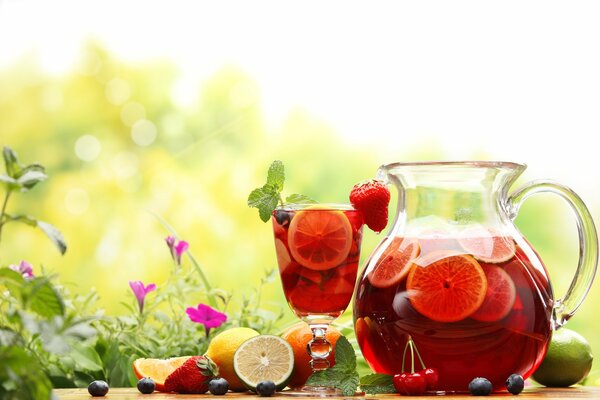 Compota de frutas y bayas en un vaso y una jarra