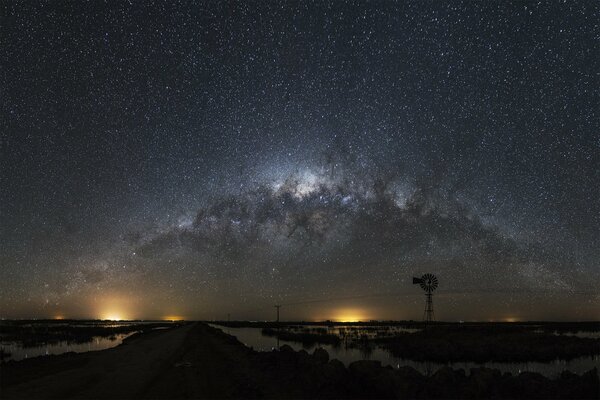 Paisaje nocturno con luces bajo el cielo cósmico