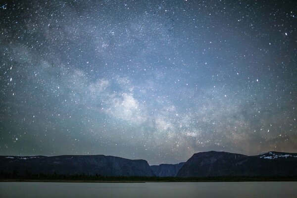 Nachtsee erhellt das Ufer mit Sternenhimmel