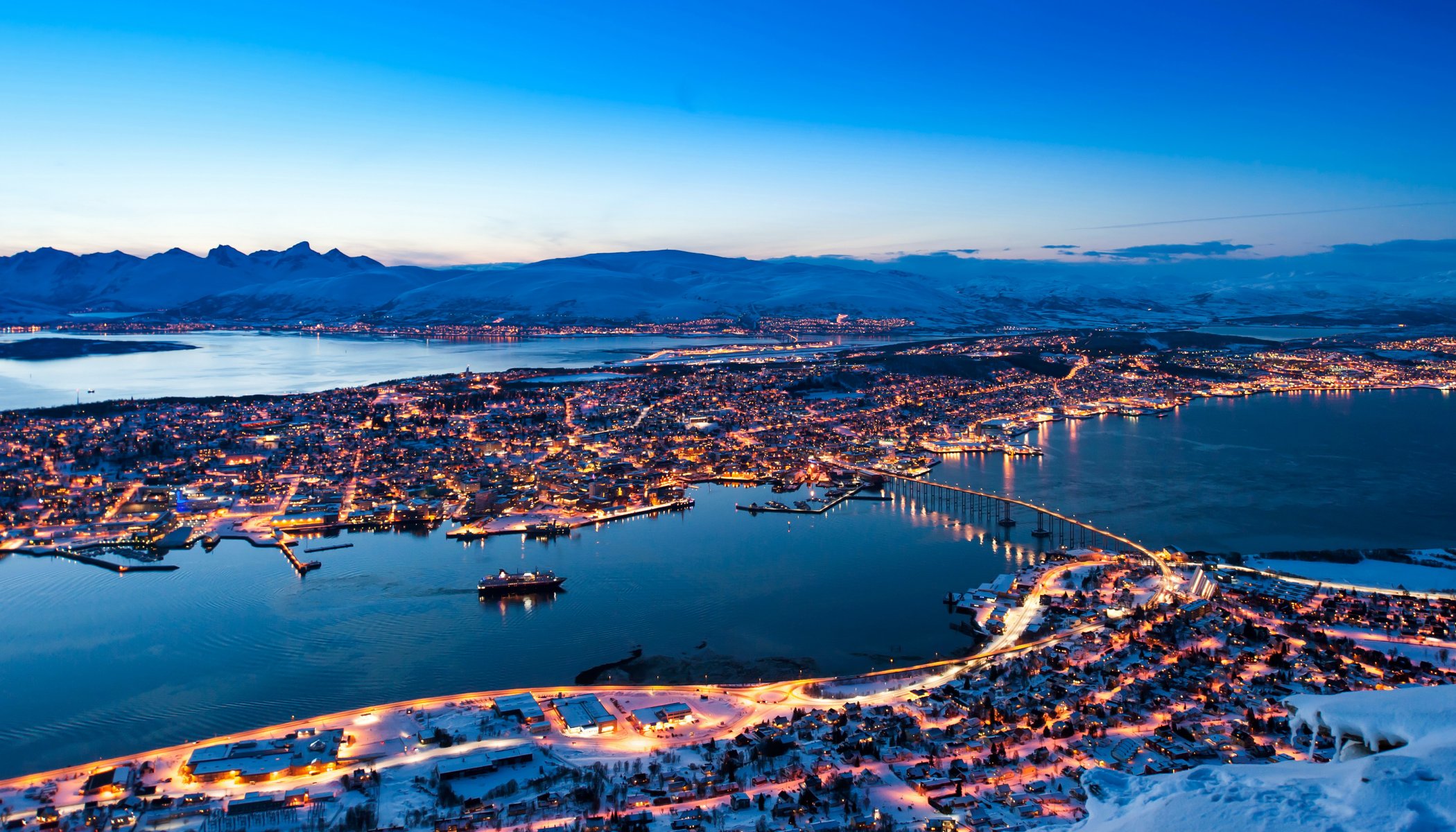 norwegia tromso wieczór zima góry śnieg domy światła most ulice panorama krajobraz