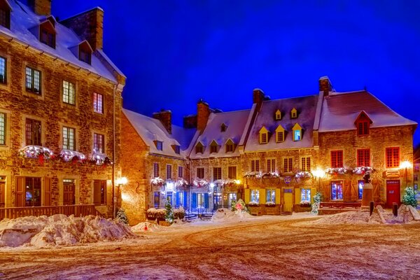 Snow-covered houses on lighted city streets