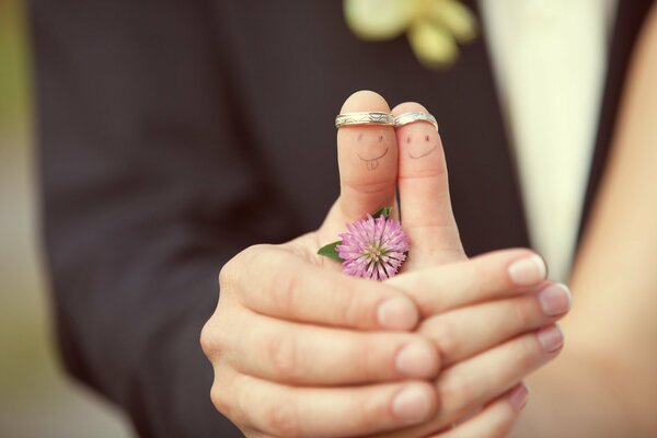 Gli sposi hanno disegnato facce sulle dita e si tengono per mano