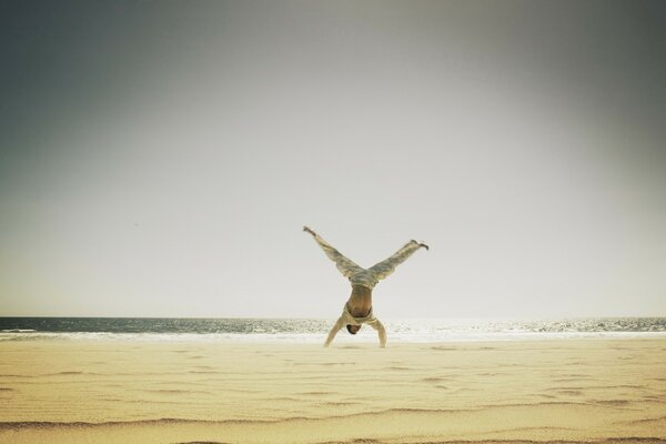 Homme sur la plage faisant la roue