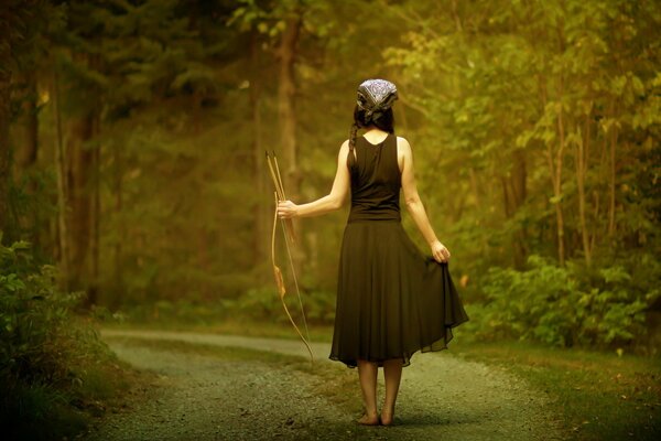A girl with a bow and arrow in the forest