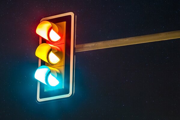 Un feu de circulation brûle de toutes les couleurs dans la nuit