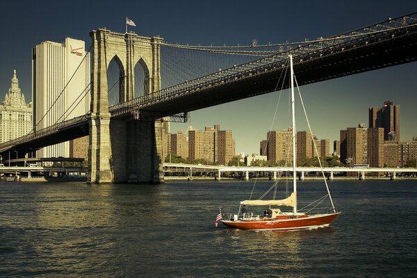 Eine Yacht, die unter der Brooklyn Bridge schwimmt