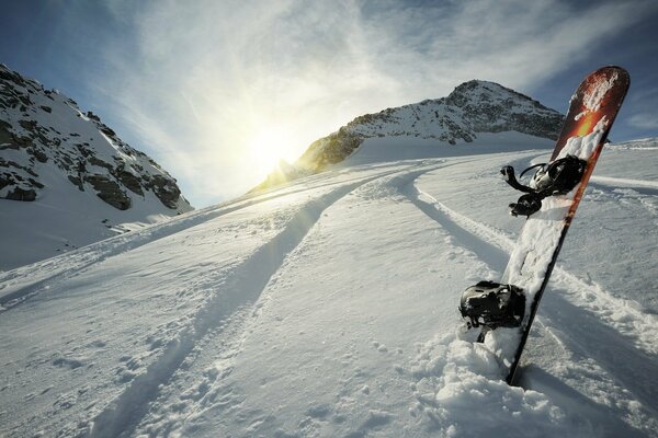 Bord im Schnee auf dem Hintergrund von Berg und Sonne
