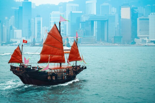 Bateau de voile écarlate dans l océan sur fond de ville