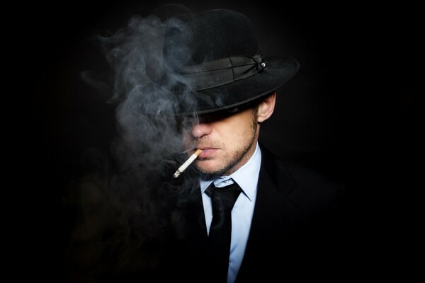 Hombre a traje, sombrero, con un cigarrillo