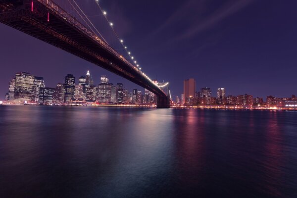 Die Brooklyn Bridge geht in der Nacht nach Manhattan
