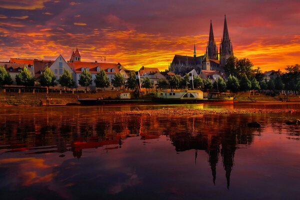 Tramonto e cielo in fiamme a Ratisbona, in Germania. Riflessione della città e della cattedrale nel fiume