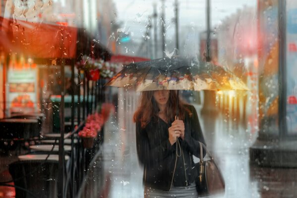 A girl under an umbrella in the summer rain in St. Petersburg