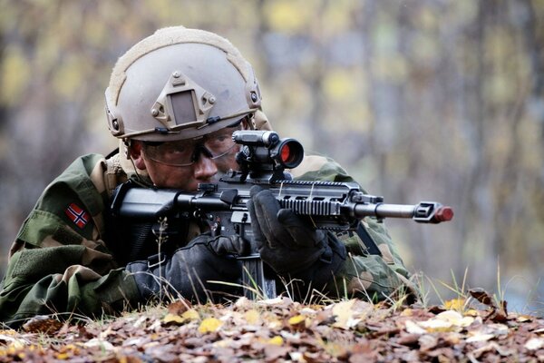 Ein Soldat mit einer Waffe liegt in einem Hinterhalt