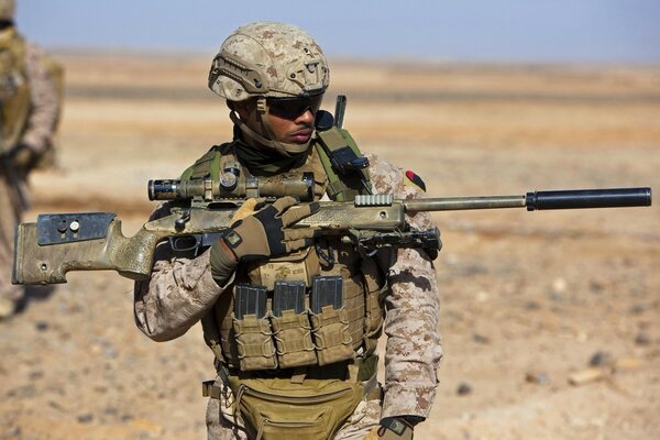 A soldier with a gun on the background of sand