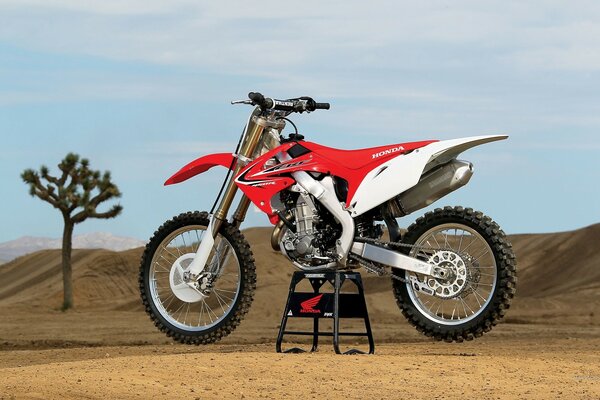 A red motorcycle stands in the middle of the desert