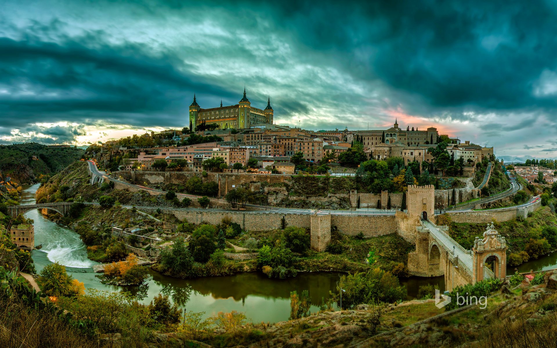 toledo españa paisaje colina castillo casas torre árboles cielo nubes puesta de sol río puente