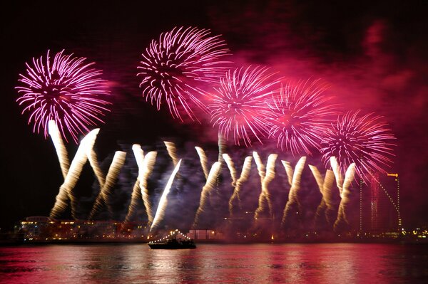 Fuegos artificiales nocturnos y colorido reflejo en el agua