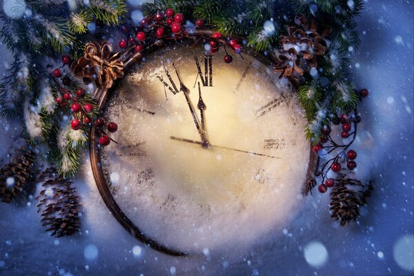 Horas de año nuevo en la nieve y ramas de abeto