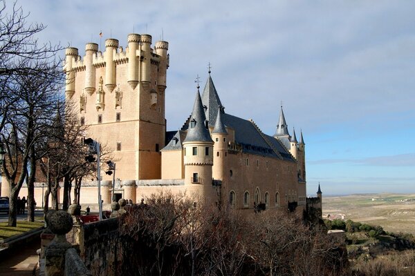 A beautiful castle with trees without leaves on a blue sky background