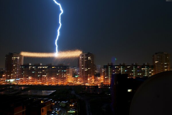 Edificios altos de Omsk y un rayo en el cielo nocturno