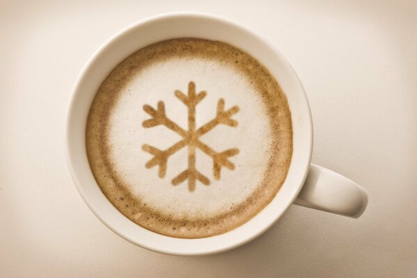 Cappuccino mit Schneeflockenmuster im weißen Becher mit