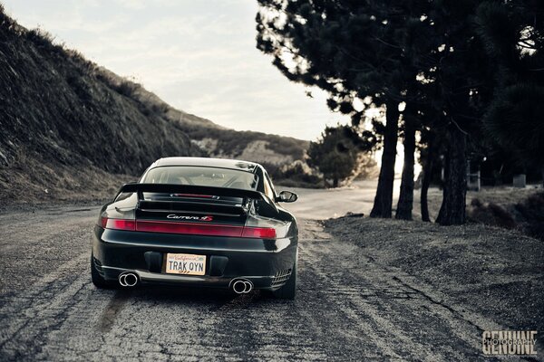 A black Porsche is driving on the road