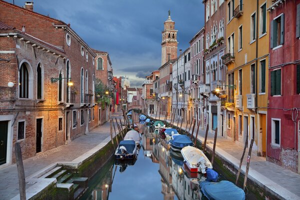 Canal estrecho con barco y en Venecia