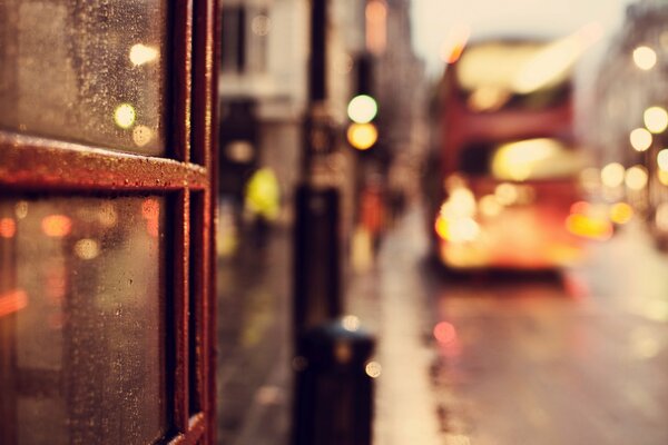 On the road, under the light of lanterns, a bus is moving under the raindrops