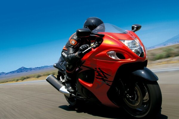 A red Suzuki motorcycle. Speed. Road. Blue clear sky