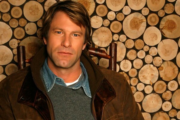 Aaron Eckhart sur une chaise en veste marron