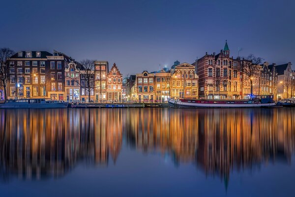 Riflessione delle case notturne di Amsterdam nel canale