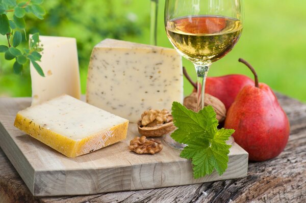 Cheese on a cutting board with white wine and pears