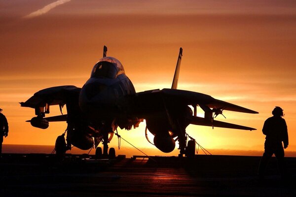 An aircraft carrier and a plane on the background of sunset