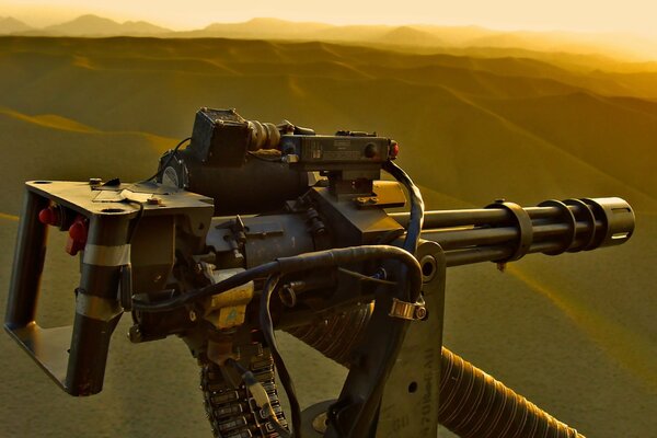 A helicopter with an m134 machine gun flies in the desert