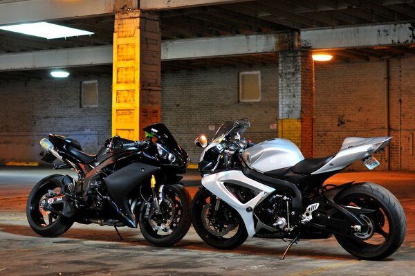 A black motorcycle and a white motorcycle look at each other