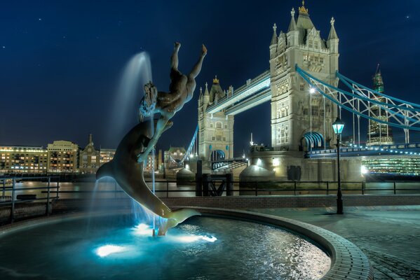 Schöner Brunnen mit Lichtern auf dem Hintergrund der Tower Bridge