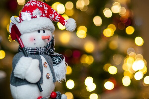 Schneemann Spielzeug mit Schaufel vor dem Weihnachtsbaum