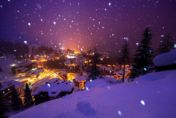 Hermosa vista del pueblo cubierto de nieve en luces brillantes