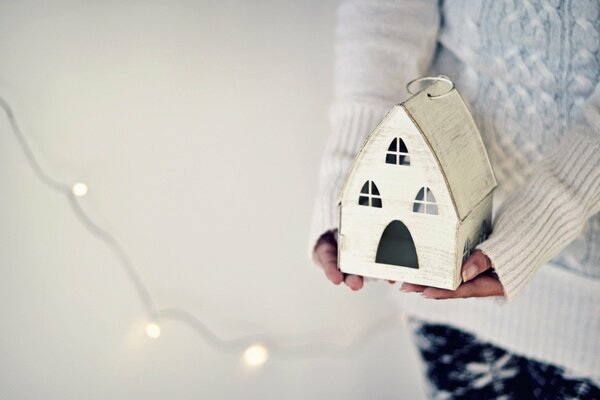 A house in the hands of a holiday sweater