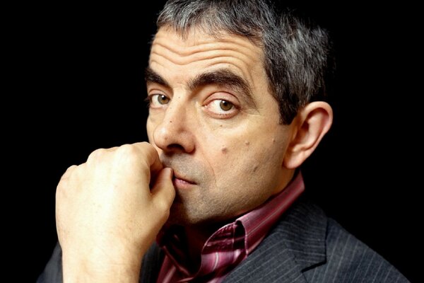 Rowan Atkinson hält seine Hand in der Nähe des Mundes